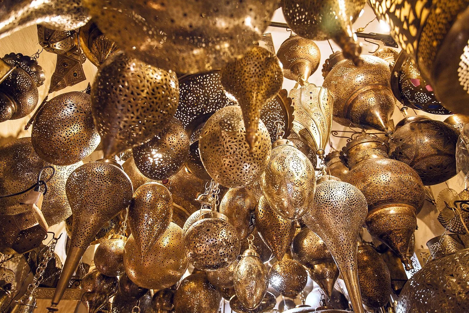 From below of assorted ornamental Moroccan lamps with tiny holes on shiny surface in local market.Lanterns in Morocco