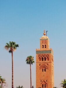 Iconic Koutoubia Mosque tower with palm trees in Marrakech against a clear blue sky.Tijdsverschil Marokko België