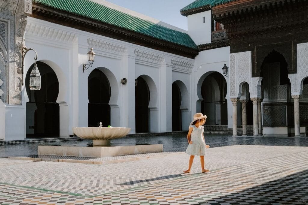 A child explores the historic Al-Qarawiyyin Mosque courtyard in Fes, Morocco on a sunny day.autistic child