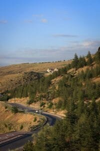 From above scenic view of empty asphalt road near hill with yellow grass and coniferous green trees under blue sky.Ifrane National Park