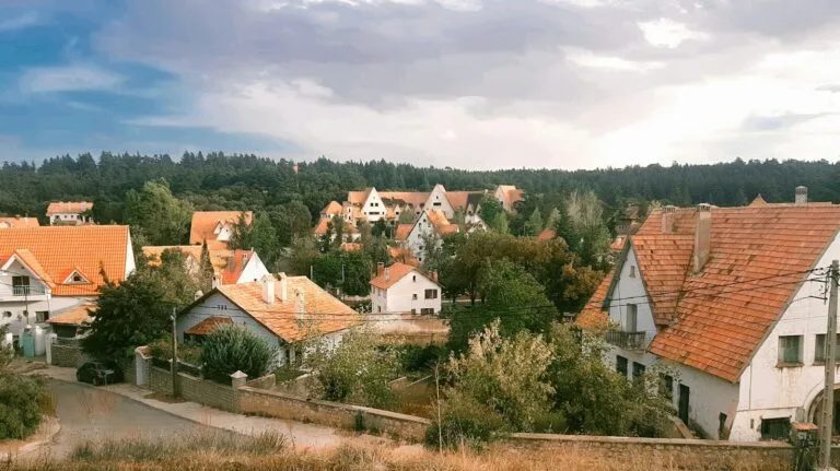 white and brown concrete house surrounded by green trees under white clouds during daytime.Ifrane National Park
