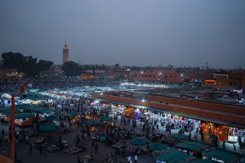 Aerial view of lively evening marketplace in Marrakech, filled with people and vibrant stalls..Language in Morocco