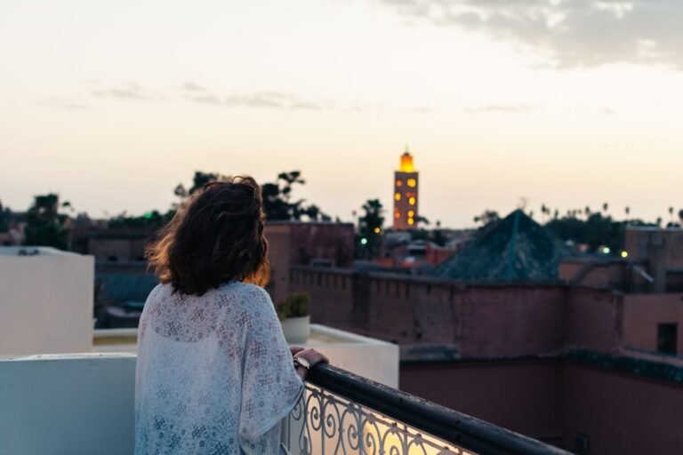A woman gazes at the evening skyline of Marrakech, appreciating the sunset from her hotel balcony.Language in Morocco