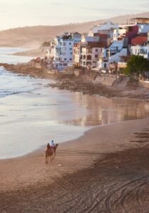 person in black shirt walking on seashore during daytime.Taghazout Beach