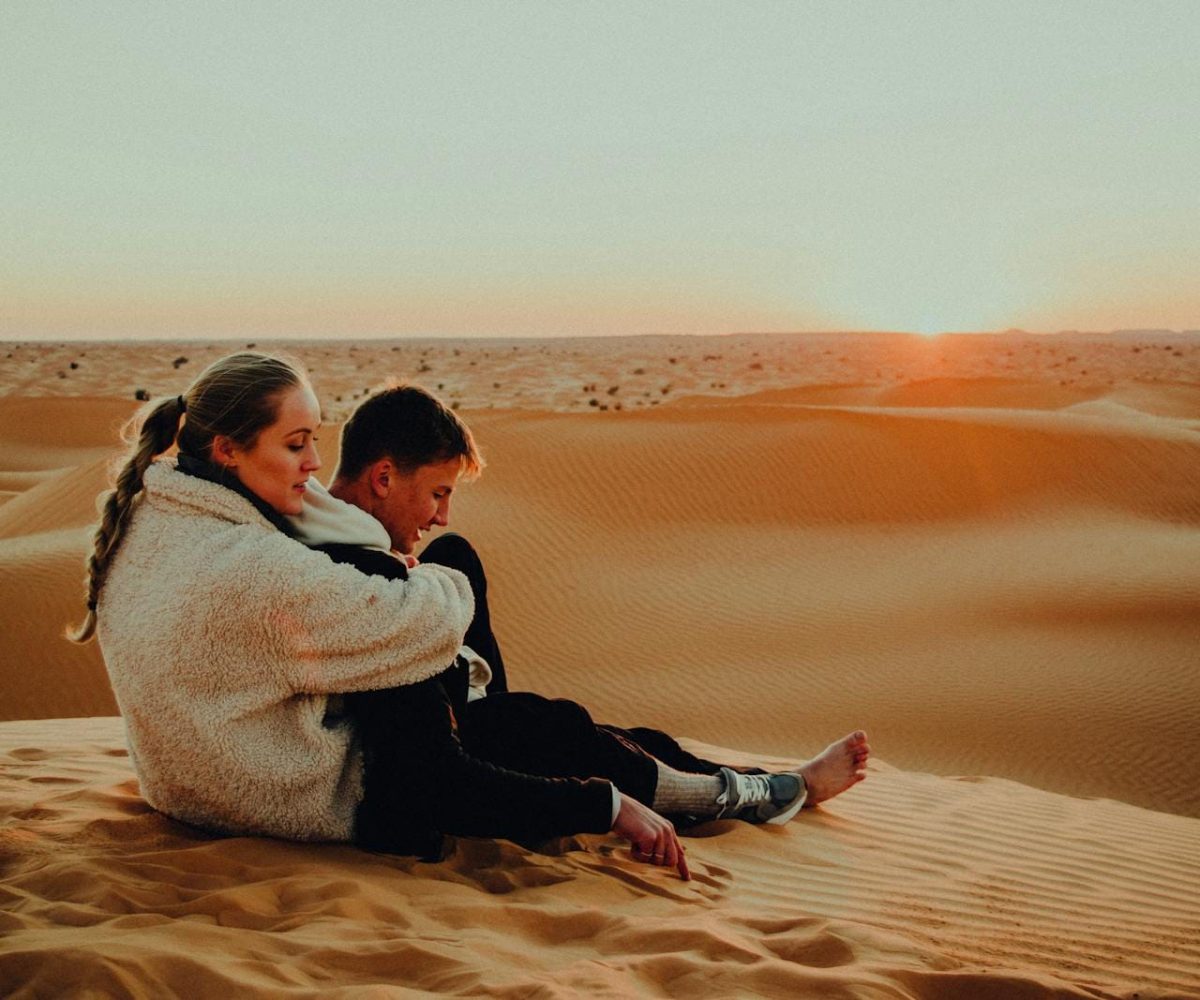 A couple enjoys a serene sunset in the vast sand dunes of Tunisia, creating a moment of tranquility and connection.3 days desert tour from Fes to Marrakech