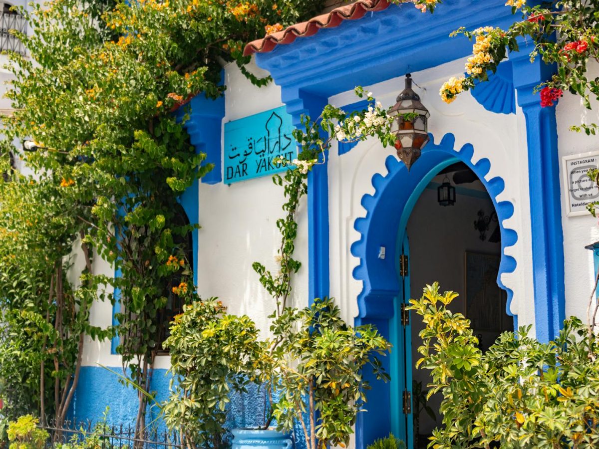Beautiful blue-and-white building entrance adorned with lush greenery in Chefchaouen, Morocco.11 days tour from Casablanca