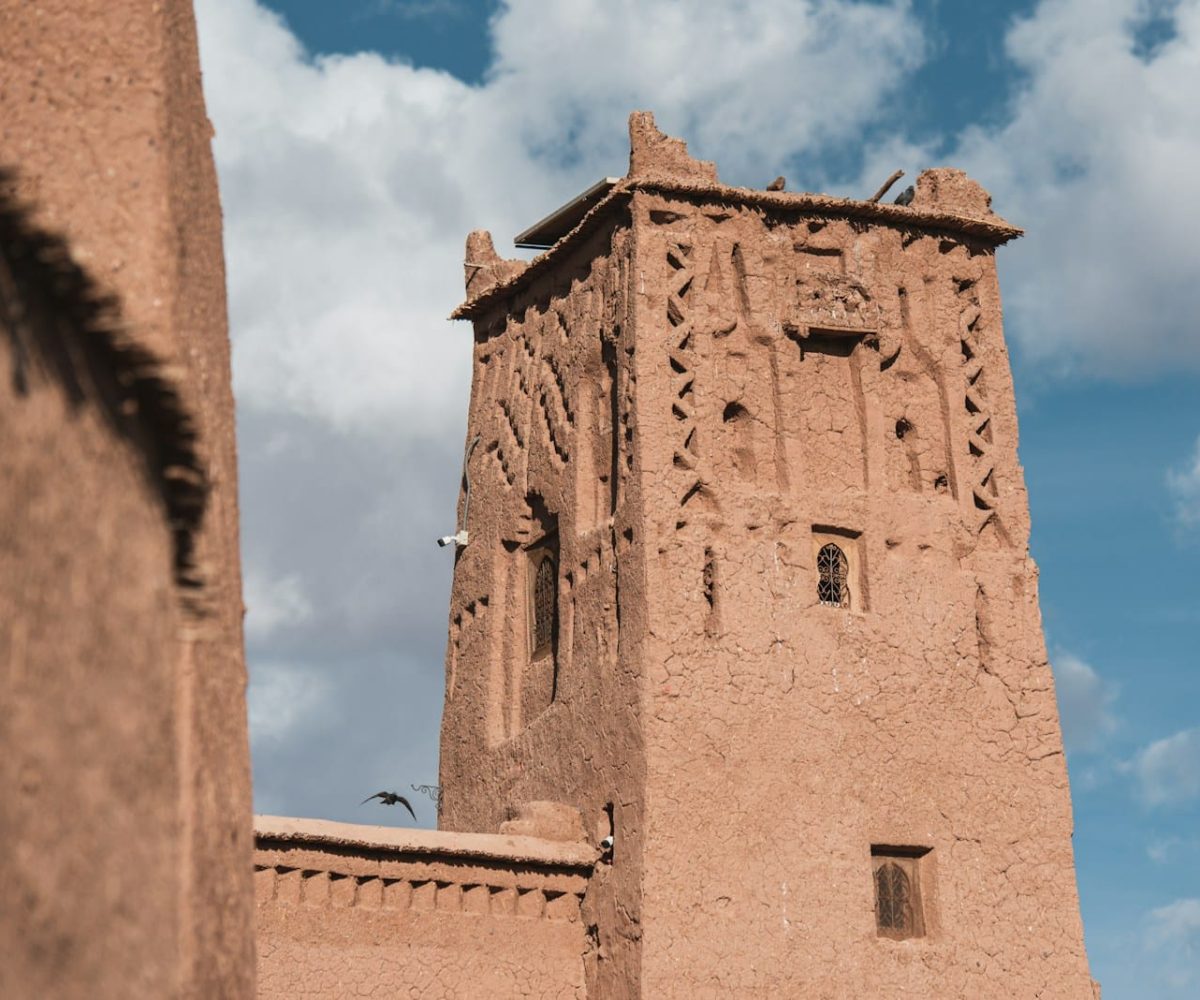 a tall brown building with a sky background,marrakech to merzouga
