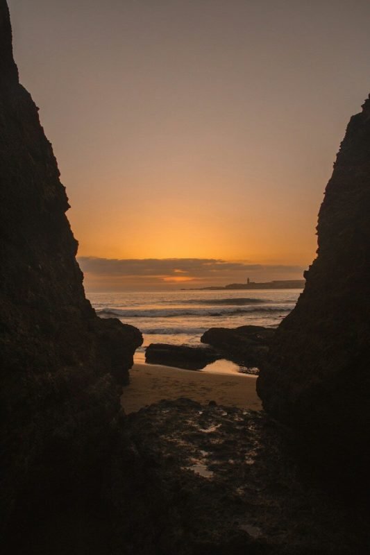 the sun is setting over the ocean and rocks.Essaouira Beach.Best beaches in Morocco