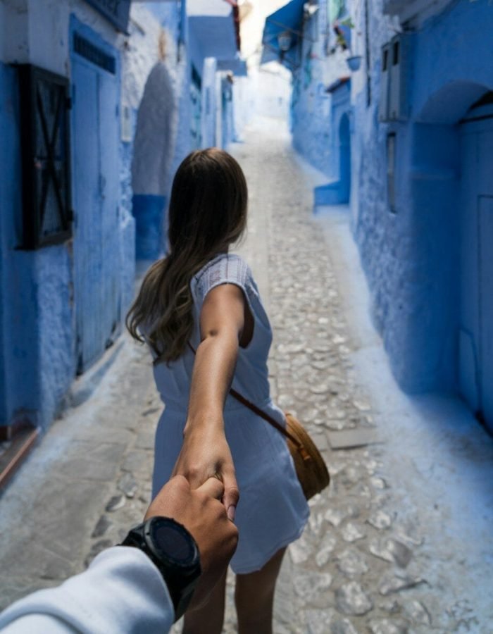 woman holding man's hand while walking on alley
