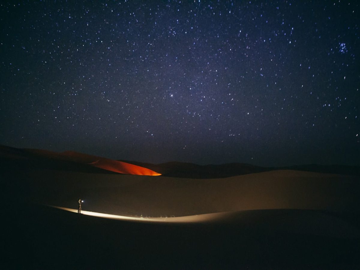 a person standing in the middle of a desert at night